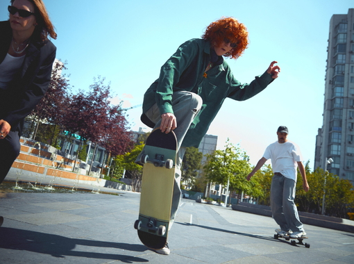 Burst of energy. Dynamic image of stylish men, skaters in motion in public place, park, training, riding on skateboard.