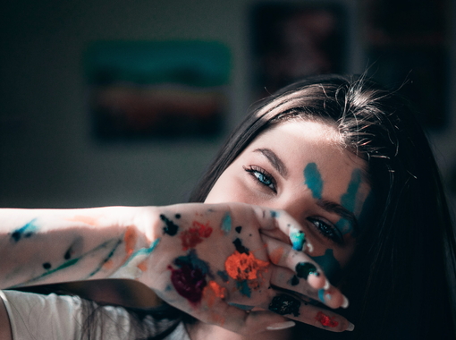 Artist girl with a handprint on face. Concept: art with paint.